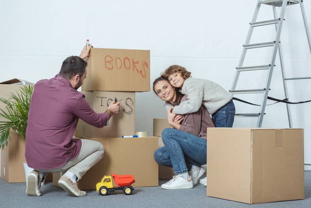 счастливая семья подписывает ящики во время переезда в новый дом
 - Фото, изображение