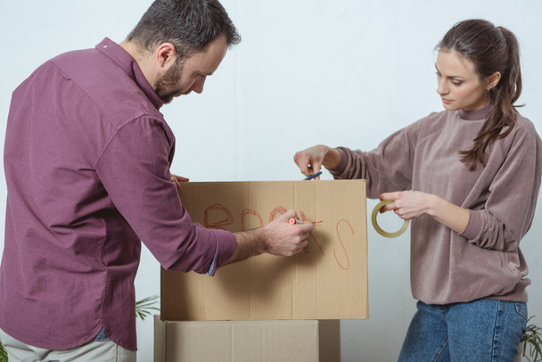 young couple packing boxes while moving in new house - Foto, imagen