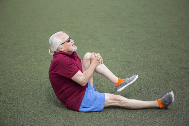 Vanhempi mies harjoittelee urheilustadionilla ulkona. Terveellisen elämäntavan käsite ja urheilukoulutuksen saatavuus jokaiselle henkilölle. Käytettävissä olevat urheiluvälineet julkisella paikalla
. - Valokuva, kuva