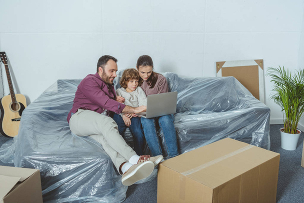 famille avec un enfant utilisant un ordinateur portable tout en déménageant dans un nouvel appartement
  - Photo, image