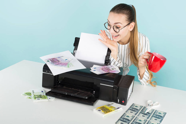Chica bonita en gafas con estilo de impresión de dinero falso en la impresora moderna y la celebración de la taza roja
  - Foto, imagen