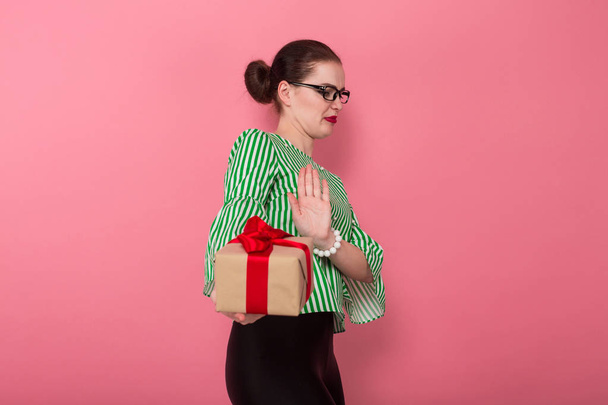Δυσαρεστήθηκε όμορφη νεαρή γυναίκα σε κομψά γυαλιά κρατώντας κιβώτιο δώρων  - Φωτογραφία, εικόνα