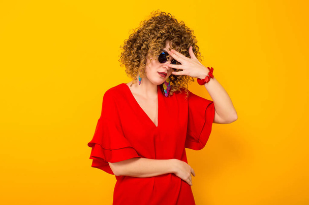 Attraente giovane donna dai capelli ricci in abito rosso e occhiali da sole
  - Foto, immagini