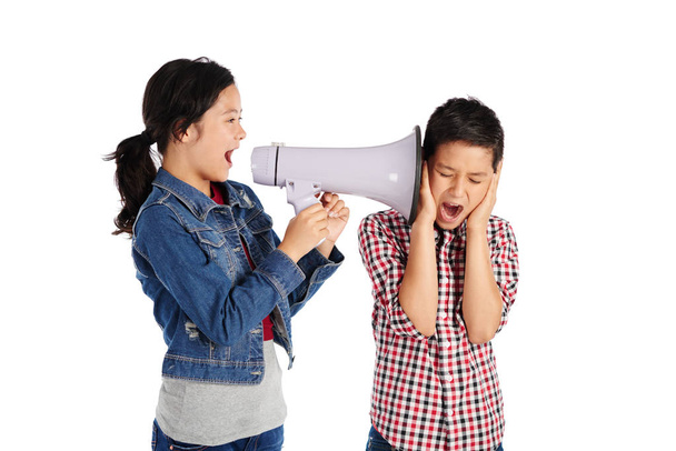 Boy covering ears as his sister is shouting at him in megaphone - Фото, зображення