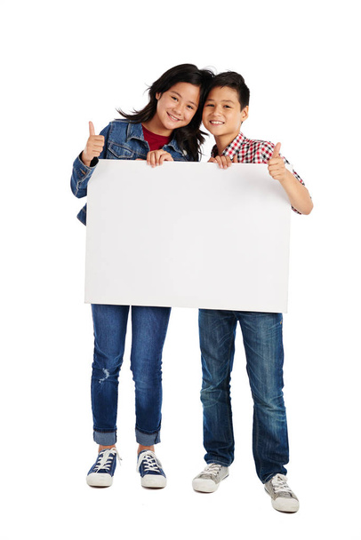 Emocionados niños de raza mixta sosteniendo un gran cartel vacío
 - Foto, Imagen