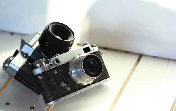 Dvě černé staré školy ročníku filmové fotoaparáty na bílých dřevěných prken, slunný interiér - Fotografie, Obrázek
