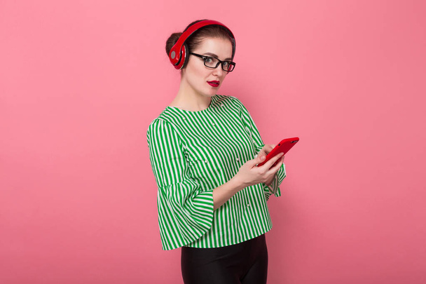 Houkutteleva nuori brunette nainen punainen kuulokkeet tekstiviestit älypuhelimella
  - Valokuva, kuva