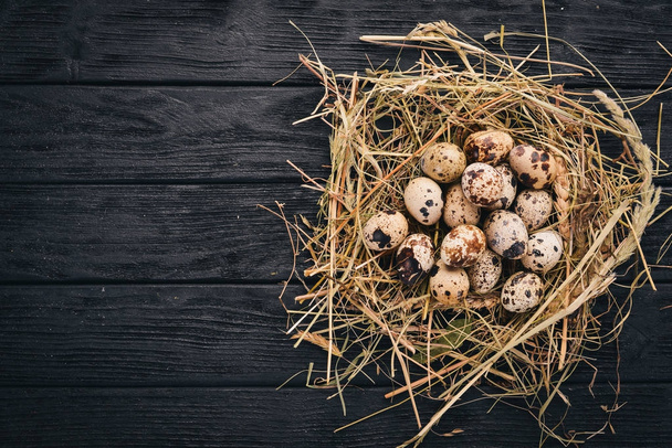 Quail eggs in the hay. On a wooden background. Top view. Copy space. - Valokuva, kuva