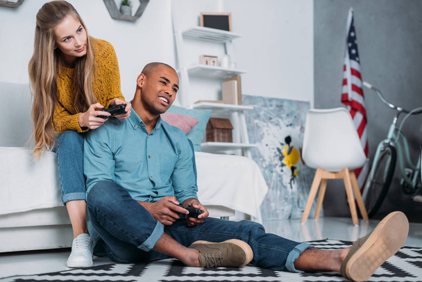 pareja multicultural jugando videojuego en casa
 - Foto, imagen