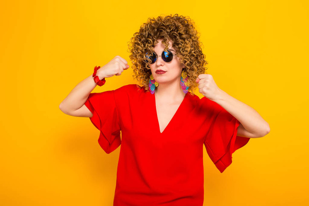 Angry young curly haired woman in red dress and sunglasses fighting - Foto, Imagem