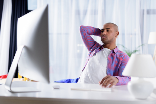 tired african american man looking at computer at home - Foto, Bild