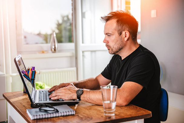 Man in black shirt working on laptop - Photo, Image