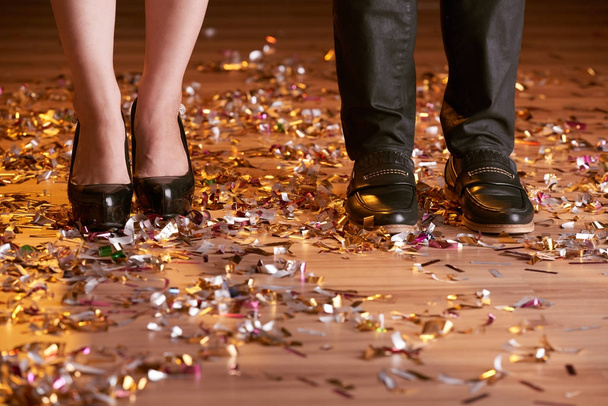 Feet of couple standing on club floor with confetti - Фото, изображение