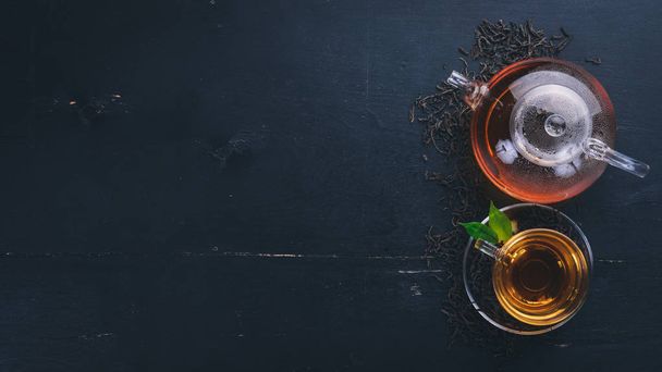 Tea in a glass cup with spices and herbs. On a black wooden background. Top view. Copy space. - 写真・画像