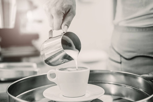 Black and white image of woman pouring cream or milk into cup of coffee - Φωτογραφία, εικόνα