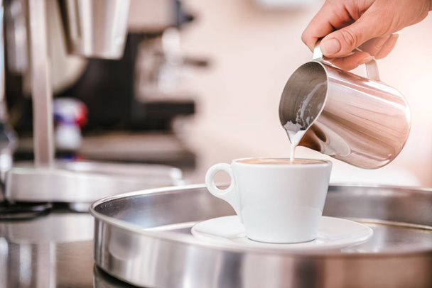 Woman pouring cream or milk into cup of coffee - Photo, Image
