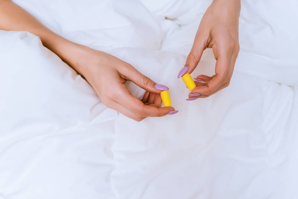 woman holding earplugs on the bed background - Foto, afbeelding