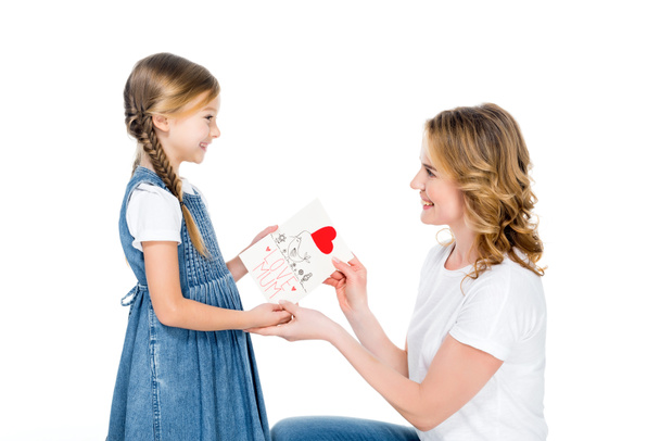 smiling daughter giving greeting card to mom, isolated on white, mothers day concept - 写真・画像