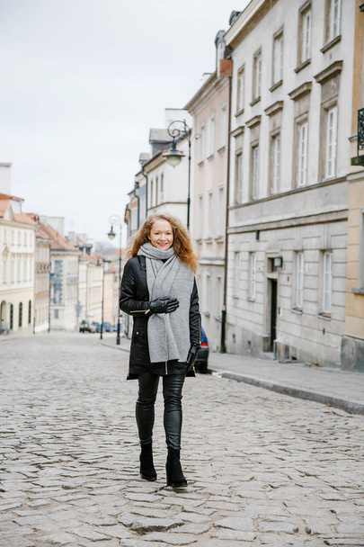 Travel the old city. A young woman travels. Market Square in Warsaw. Curly girl walks through the streets of the city. - Foto, Imagem