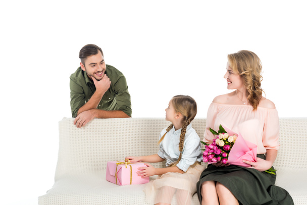 hombre mirando feliz familia con regalos en sofá aislado en blanco
 - Foto, Imagen