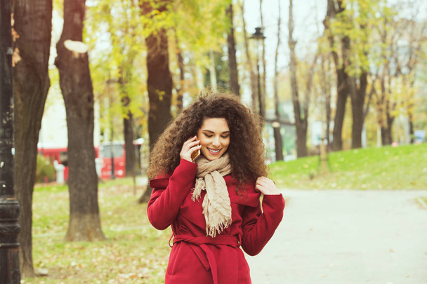 beautiful woman in red jacket, with mobile phone - Фото, изображение