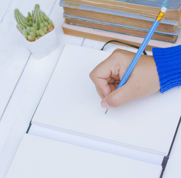 Женская рука с весенней рубашкой пишет что-то карандашом
  - Фото, изображение