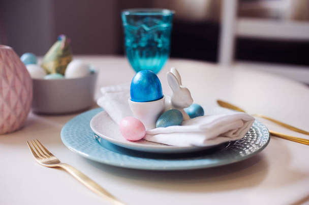 easter and spring festive table decorated in pink and blue colours with modern golden metalic cutlery, eggs and bunny.  - Valokuva, kuva