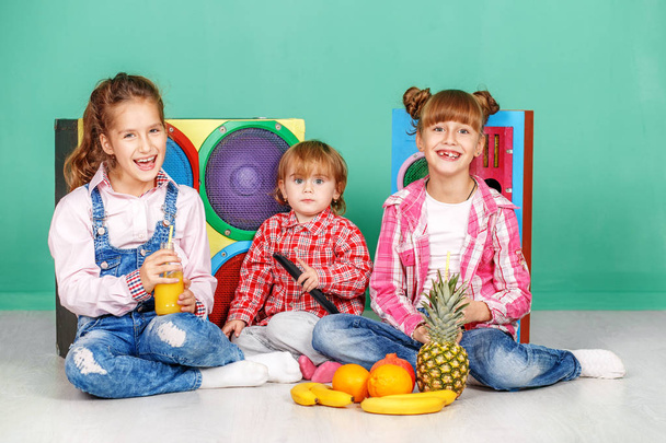 Трое детей смотрят телевизор и едят фрукты
.  - Фото, изображение