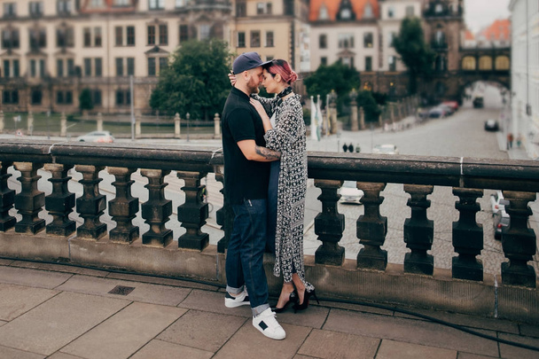 κομψό νεαρό ζευγάρι στην αγάπη αγκάλιασμα ενώ στέκεται στη γέφυρα στη Δρέσδη, Γερμανία  - Φωτογραφία, εικόνα