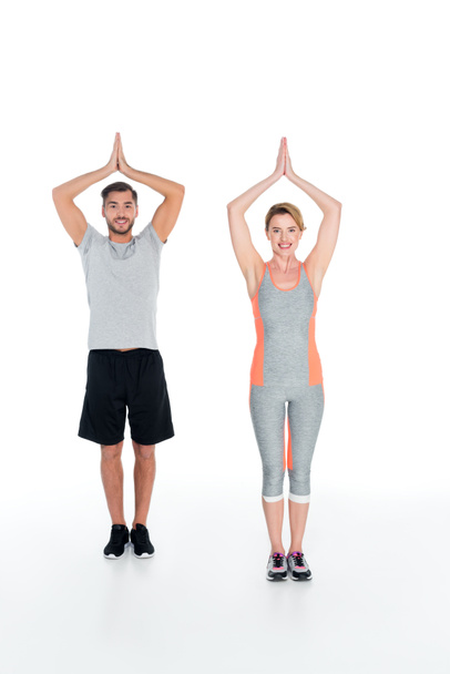 Lächelndes Paar in Sportkleidung praktiziert Yoga isoliert auf Weiß - Foto, Bild