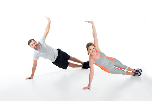 smiling sportive couple exercising together isolated on white - Fotó, kép