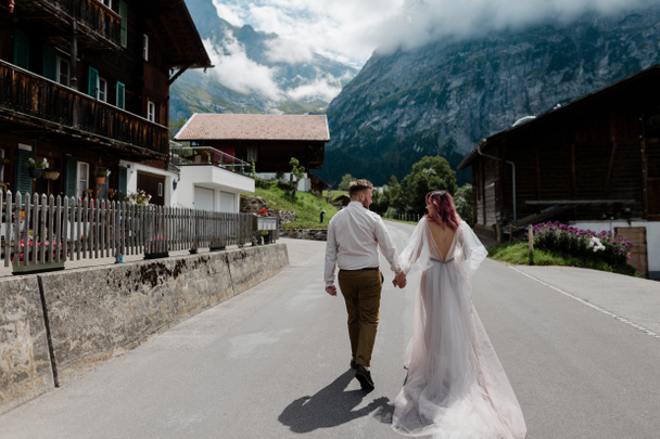 vue arrière du couple tenant la main et marchant sur la route en ville dans les Alpes
 - Photo, image