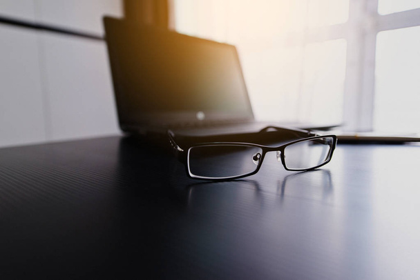 Glasses on laptop computer with pen on desk - Φωτογραφία, εικόνα