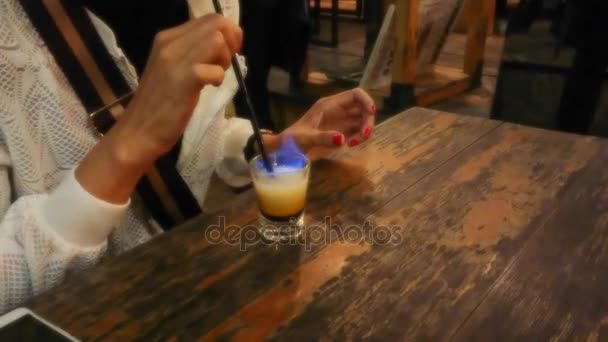 Vrouwelijke vlammende drankje met rietje drinken in een café-restaurant in dromerige stijl - Video