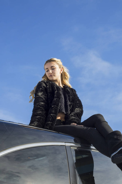 young woman sitting on car in winter - Valokuva, kuva