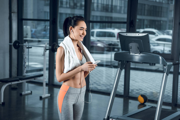 young fit woman listening music with earphones at gym - Photo, Image