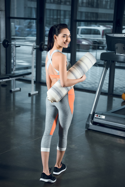 young fit woman with rolled yoga mat at gym - Foto, Bild