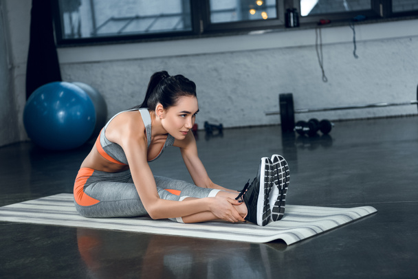 young sporty woman doing forward bend on yoga mat at gym - Φωτογραφία, εικόνα
