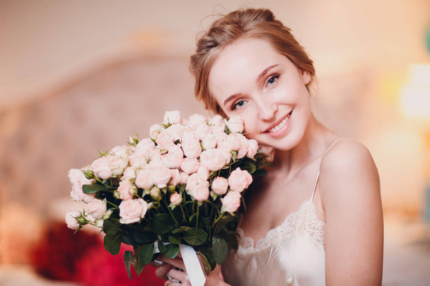 Bastante joven sonrisa femenina y mirar a la cámara y sostener las flores
 - Foto, imagen