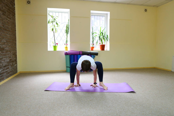 Jonge vrouw van Amerikaanse verschijning voert asana's van yoga. - Foto, afbeelding