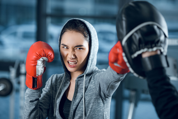 agressive young female boxer training at gym - Fotó, kép