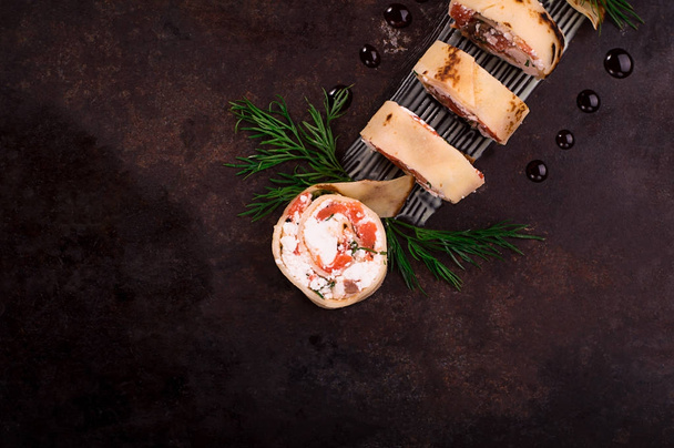 Rotoli di frittelle sottili con salmone, crema di formaggio di rafano. Vecchio sfondo nero. Vista dall'alto. Focus selettivo
 - Foto, immagini