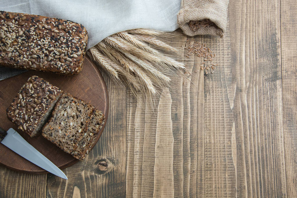 Fitness bread. A loaf of fresh rustic whole meal rye bread, sliced on a wooden board, rural food background. Copy space. - Photo, Image