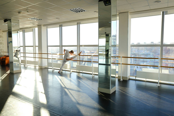 Gymnast in sportswear training near ballet barre in sport gym - Photo, Image