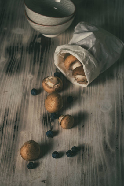 Foto vintage de vários cogumelos com tampas marrons derramadas do saco na placa de madeira
 - Foto, Imagem