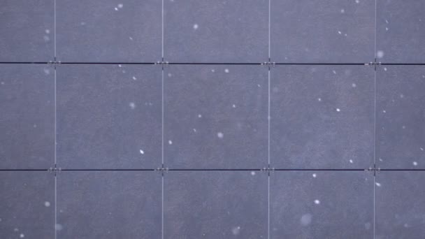 Fiocchi di neve che cadono su uno sfondo di piastrelle grigie, nevicate, fiocchi di neve, sfondo invernale
. - Filmati, video