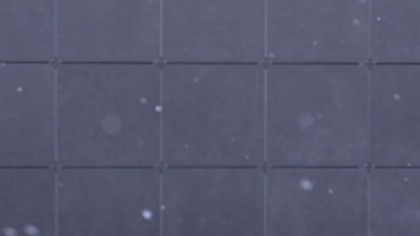 Schneeflocken fallen auf eine graue Fliese defokussiert Hintergrund, Schneefall, Schneeflocken, Winter Hintergrund. - Filmmaterial, Video