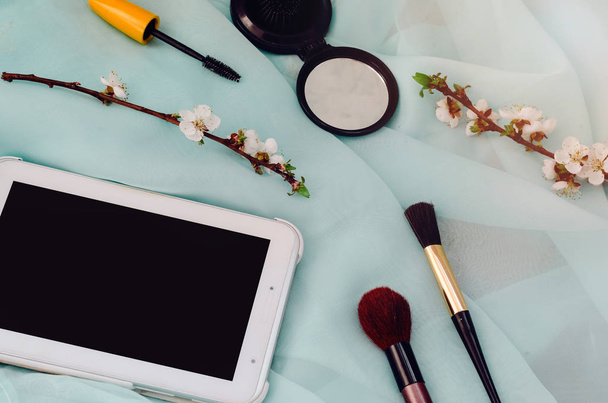 una tableta para la comunicación. belleza y moda. kit de cuidado facial femenino. cepillos de maquillaje
 - Foto, imagen