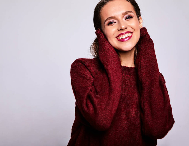 Portrait of beautiful happy cute brunette woman model in casual warm red sweater clothes isolated on gray with evening makeup and colorful lips - Photo, image