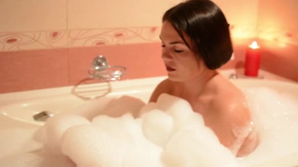 Zwemmen jonge vrouw ontspannen in bad. Vrouw geniet het badschuim in de badkuip. - Video